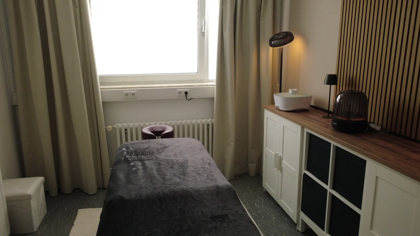 Blick auf die Liege und Holzlamellen im Massageraum